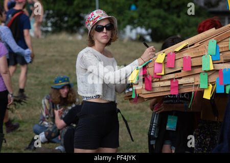 Glanusk Park, Brecon, Galles, 18 agosto 2018. Secondo giorno del festival musicale Green Man nelle Brecon Beacons Mountains in Galles. PA giovani donne scrive una nota alla statua dell'uomo Verde. Foto generiche della folla e del sito durante il festival. Crediti: Rob Watkins/Alamy Live News Foto Stock