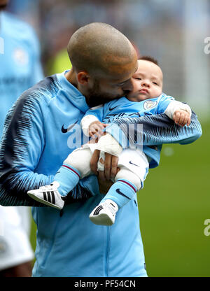 Manchester City David Silva passeggiate fuori sul campo con il suo neonato figlio Mateo all inizio del match di Premier League al Etihad Stadium e Manchester. Foto Stock