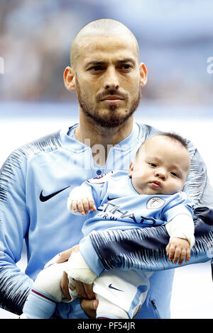 Manchester City David Silva passeggiate fuori sul campo con il suo neonato figlio Mateo all inizio del match di Premier League al Etihad Stadium e Manchester. Foto Stock