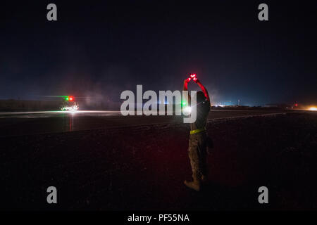 Un U.S. Air Force elicottero maintainer assegnato all'801st manutenzione Expeditionary Squadron esegue il marshalling di un HH-60G Pavehawk assegnato alla quarantaseiesima Expeditionary squadrone di salvataggio come taxi verso il basso di una linea di volo prima di una missione in una località segreta, Iraq, a sostegno di operazioni inerenti a risolvere, e il Agosto 8, 2018. La missione primaria di HH-60G Pave Hawk elicottero è di condurre di giorno o di notte personale le operazioni di ripristino in ambienti ostili per recuperare personale isolato durante la guerra. In collaborazione con le forze di partner, Combined Joint Task Force - Funzionamento inerenti risolvere sconfitte ISIS in d Foto Stock