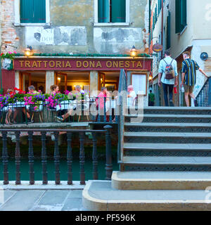Venezia, Italia - 18 Giugno 2018: persone al piccolo ristorante con tavoli all'aperto vicino al piccolo canale di Venezia Foto Stock