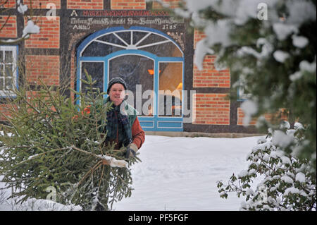 Mann Weihnachtsbaum trägt im Schnee | uomo porta albero di Natale home, camminando attraverso la neve profonda Foto Stock
