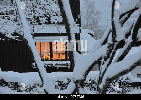 Haus beleuchtet mit Schnee bedeckt | casa coperte di neve e una finestra illuminata Foto Stock