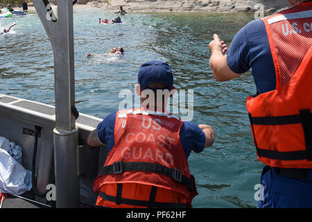 Petty Officer di 2a classe di Jason Bravo, Macchinario Tecnico, Coast Guard ausili alla navigazione Team San Diego e Cmdr. Kris Szczechowicz, capo del dipartimento di prevenzione, Coast Guard Settore San Diego, prepararsi a prendere a bordo un floater feriti nei pressi di Big Bend del Colorado State Recreation Area, Laughlin, Nevada, durante la Laughlin regata sul Fiume 11 Agosto, 2018. Il galleggiante è stato ferito dopo il tentativo di una rupe saltare durante l'evento. (U.S. Coast Guard foto di Sottufficiali di 2a classe di Joel Guzman/rilasciato) Foto Stock