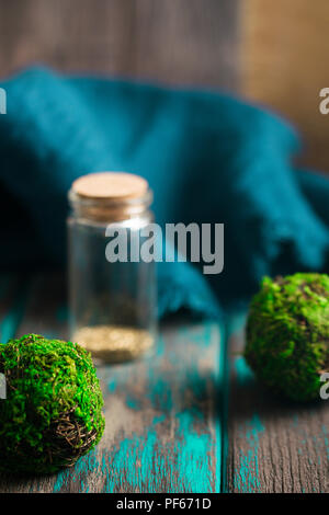 Alchemy oro in vetro piccola bottiglia. Le sfere di muschio e rustico scrivania in legno. Magia e Stregoneria concetto. Foto Stock