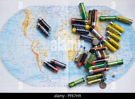 Batteris vuoto su uno usato solo versato sulla mappa del mondo. Foto Stock
