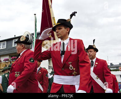 Usseln, Germania - Luglio 29th, 2018 - i soci di un club di fucile indossando la loro tradizionale divisa rossa omaggio a una sfilata alla tiratori giusto Foto Stock