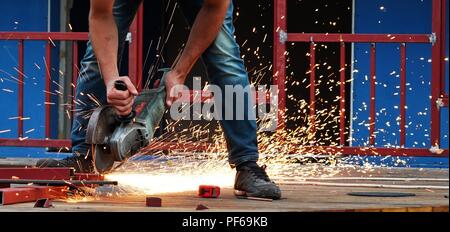 Lavoratore di metallo taglio acciaio sul sito in costruzione, scintille volanti Foto Stock