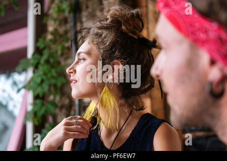 Dai capelli scuri donna che indossa abiti neri cercando nella finestra Foto Stock