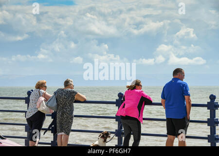 La gente appoggiata sulle ringhiere sul lungomare di Porthcawl, Galles, che si affaccia sul Canale di Bristol Foto Stock