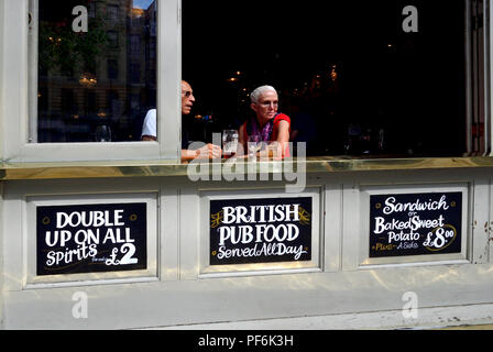 La gente alla finestra aperta del Garrick Arms pub in Charing Cross Road, Londra, Inghilterra, Regno Unito. Foto Stock