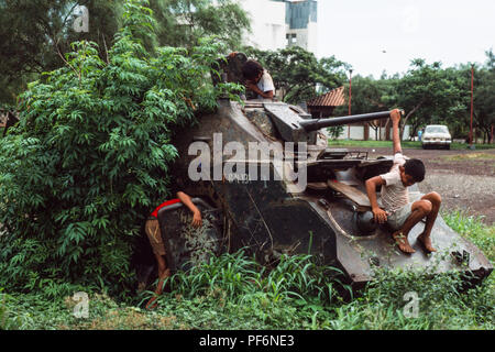 Managua, Nicaragua, giugno 1986; i bambini giocano sul scatafascio resti di Somoza di carri armati e APC nel centro di Managua. Vi erano destryed dalle forze sandinista in guerra civile contro Somoza nel 1979. Foto Stock