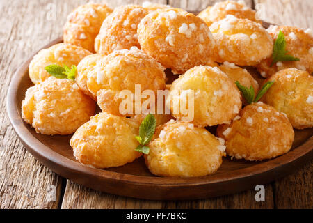 Heap francese Bignè choux con perla di zucchero e di macro di menta su una piastra su un tavolo. Posizione orizzontale Foto Stock