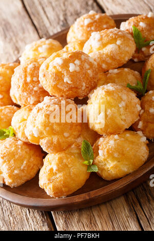 Francese dessert chouquette profiteroles con zucchero perlato e menta closeup sul piano verticale. Foto Stock