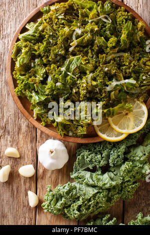 Cibo vegetariano: fritto di cavolo verza con cipolle e aglio close-up su una piastra. Verticale in alto vista da sopra Foto Stock