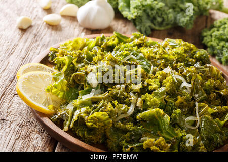 Deliziosa kale, cipolle, aglio e limone close-up su una piastra e gli ingredienti sul tavolo orizzontale. Foto Stock
