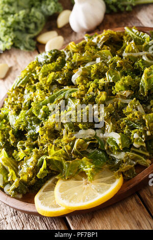 Cibo vegetariano: fritto di cavolo verza con cipolle e aglio close-up su una piastra verticale. Foto Stock