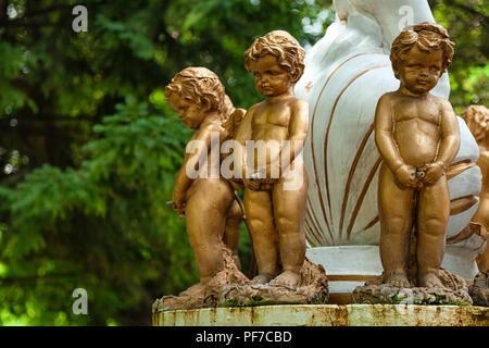 Close-up di tre little angel boys statue, coperto con base di bronzo su una fontana nel parco della città Foto Stock