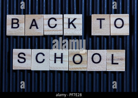 Si torna a scuola raccolti dalla lettera di legno blocco sul mazzo di matite nero lo sfondo Foto Stock