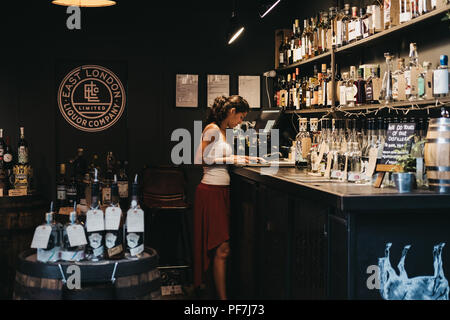 London, Regno Unito - 24 Luglio 2018: Venditore disponendo la documentazione a est di Londra Liquor azienda stand al Mercato di Borough, uno dei più grandi e più antiche cibo mar Foto Stock