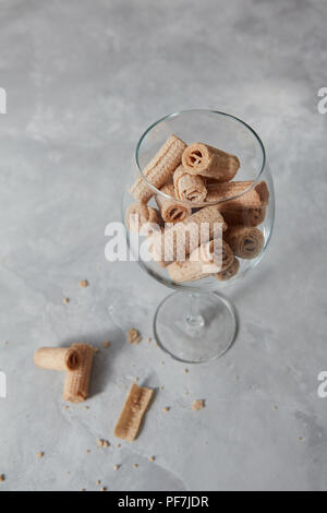 Tubi di dolci wafer in un vetro isolato su un cemento grigio Sfondo. Foto Stock