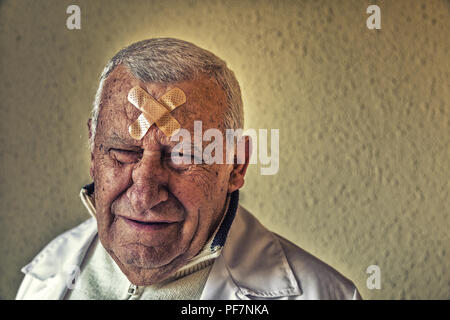 Triste vecchio medico con patch sulla fronte Foto Stock