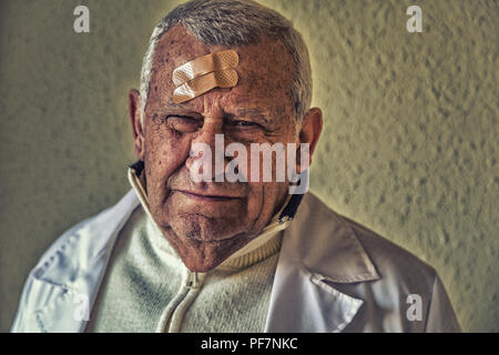 Il vecchio medico con patch sulla fronte Foto Stock