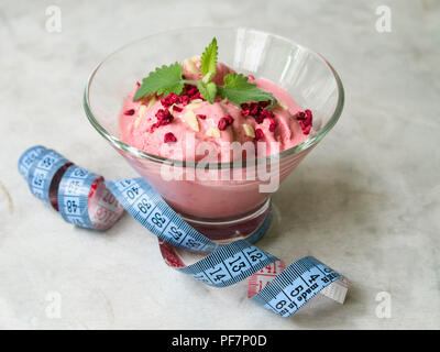 Una sana a basso contenuto calorico dessert estivo. Yogurt fatto in casa gelato alla fragola in vetreria con la fascetta su grigio backgrouond. Dieta, pulire mangiare Foto Stock