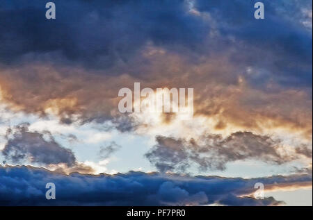 Il sole comincia a impostare su un poco nuvoloso sera d'autunno. Un sentore di viola e oro mette in evidenza sulle nuvole scurito. La natura rende il più bel abst Foto Stock