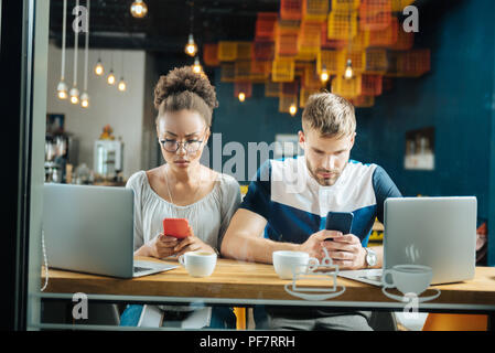 Occupato i giovani collaboratori a lavorare mentre si beve il caffè nel forno Foto Stock