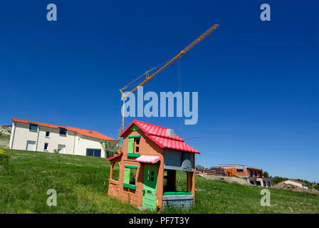 Bambini in plastica la casa su un terreno con una gru e case in costruzione, Francia Foto Stock