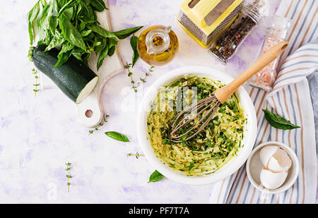 Ingredienti per la cottura di frittata con zucchine, il formaggio e il basilico. Utile di prima colazione. Omelette italiano. Vista dall'alto. Lay piatto. Foto Stock