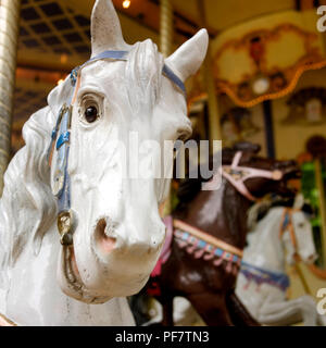Primo piano fuoco selettivo di un cavallo carosello bianco con la carosello sullo sfondo Foto Stock