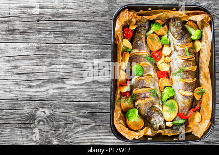 Trote intere pesci alla griglia con patate, broccoli, limone, pomodori, vista dall'alto Foto Stock