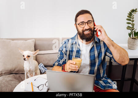 Sorridente uomo barbuto chiamando i suoi business partner di bere il caffè Foto Stock