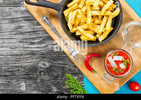 Patate fritte con pezzi di peperoncino sul piatto bianco e fette di marinato aringa norvegese in salsa di pomodoro in pezzi di pane di segale, il g Foto Stock