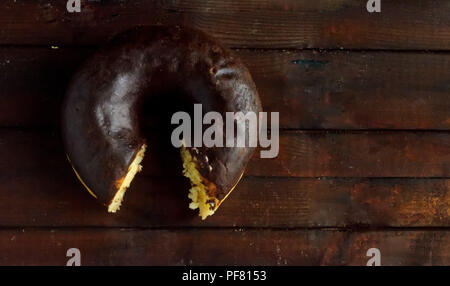 Morso ciambella di cioccolato su sfondo di legno. Foto Stock