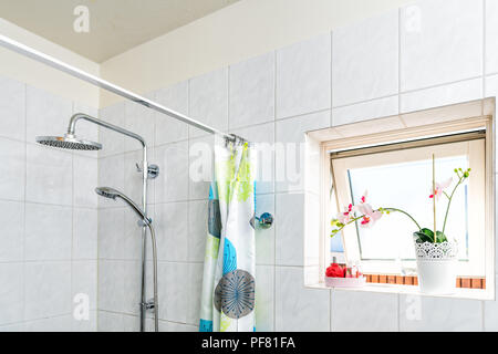 Piastrelle moderne, bagno rivestito di piastrelle con doccia, capi, tirante con anelli colorati, tenda, finestra aperta, soleggiato, la luminosa luce del sole, luce e vasi di Orchid Foto Stock