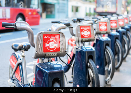 London, Regno Unito - 22 Giugno 2018: molti cicli di Santander red biciclette a noleggio, affitto, affitto in piedi, parcheggiato a docking station nel centro cittadino di fila per street, r Foto Stock