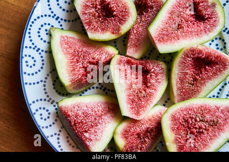 Le figure frutto su una piastra close up/macro. Il fuoco selettivo sulla sommità figure fetta nella ciotola. Tagliato le figg. Fette di fichi freschi. Foto verticale di frutta fresca Foto Stock