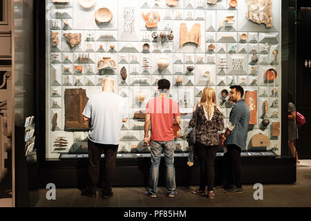 I visitatori di esaminare un caso di visualizzazione di reperti romani trovati durante il restauro del tempio di Mitra, Londra mitreo, City of London Foto Stock