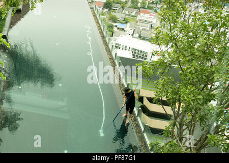 Vista dall'alto uomo pulizia resort piscina con tubo a vuoto cleaner Foto Stock