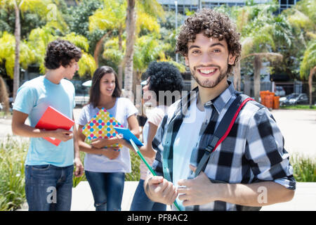 Ridendo hipster studente con un gruppo di amici all'esterno del campus in estate Foto Stock