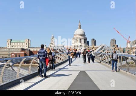 Pedoni che attraversano il Millennium Bridge con la cupola della cattedrale di St Paul in distanza, London, England, Regno Unito Foto Stock