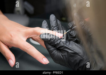 La manicurist pedicure rende la procedura di recupero e nail extensions su le unghie della ragazza in manicure . Closeup colpo di una donna in mani manicure ricevendo una manicure da una estetista Foto Stock