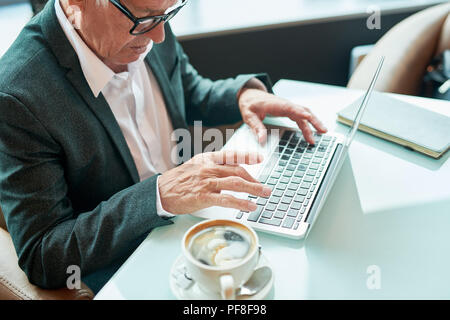 Anziani uomo d affari con computer portatile in cafe Foto Stock