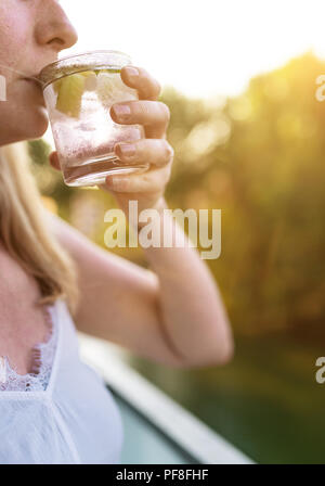 Donna bionda all'aperto a bere bevande ghiacciate Foto Stock