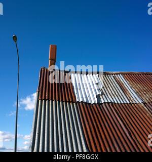 Closeup basso angolo di un vecchio tetto con un camino con una luce strada accanto ad esso. Auvergne. Francia Foto Stock