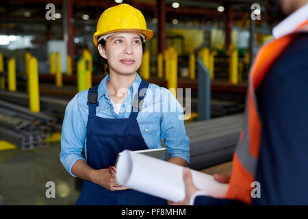Femmina operaio di fabbrica ascoltando caposquadra Foto Stock
