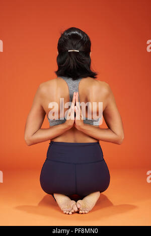 Invertire la preghiera lo yoga pone la donna mostra su arancione di sfondo per studio Foto Stock